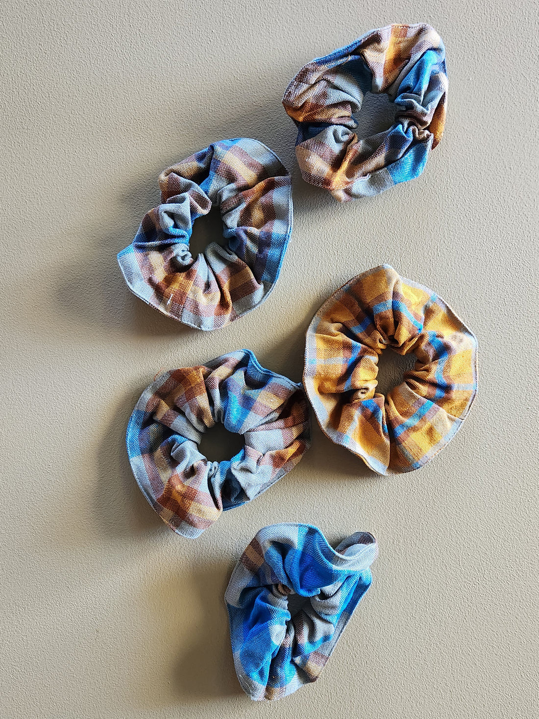 Five patterned scrunchies on a beige background
