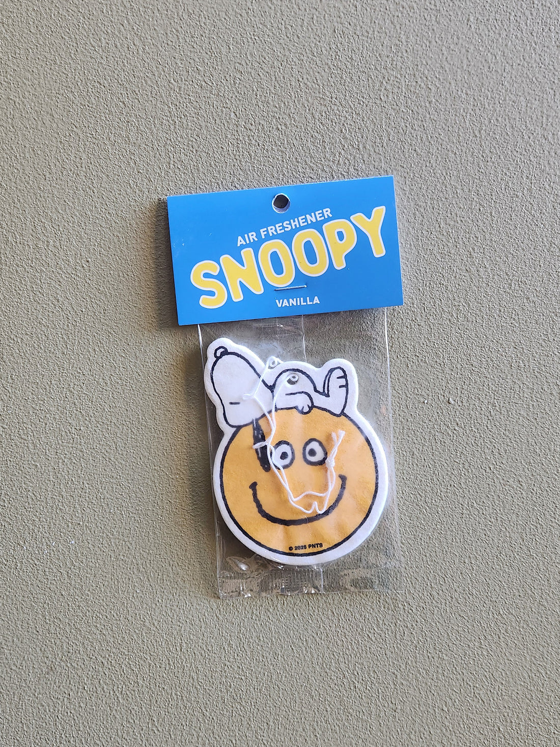 Snoopy-themed air freshener in packaging on a gray background