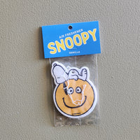 Snoopy-themed air freshener in packaging on a gray background