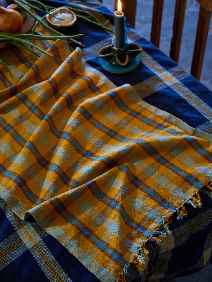 Yellow and blue checkered cloth on a table with a candle and decorative items.