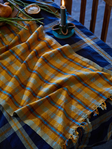 Yellow and blue checkered cloth on a table with a candle and decorative items.