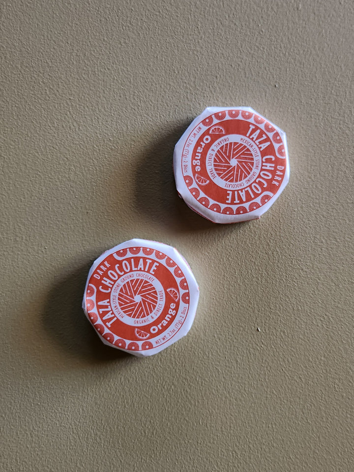 Two red and white chocolate containers on a beige surface