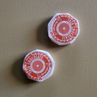 Two red and white chocolate containers on a beige surface