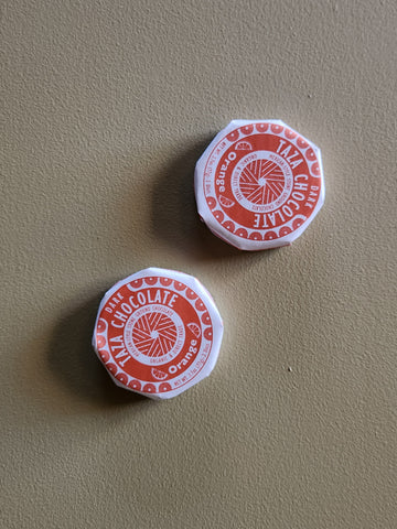 Two red and white chocolate containers on a beige surface