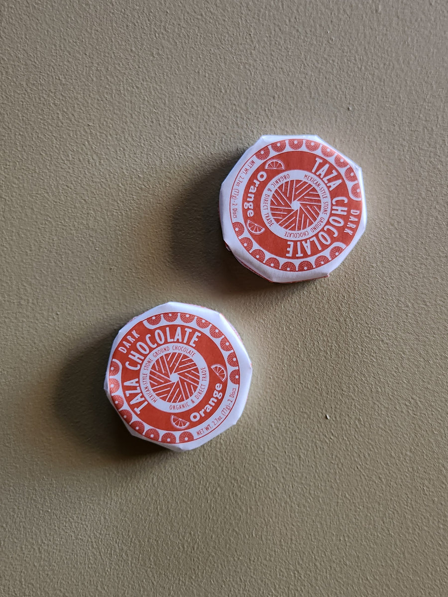 Two red and white chocolate containers on a beige surface