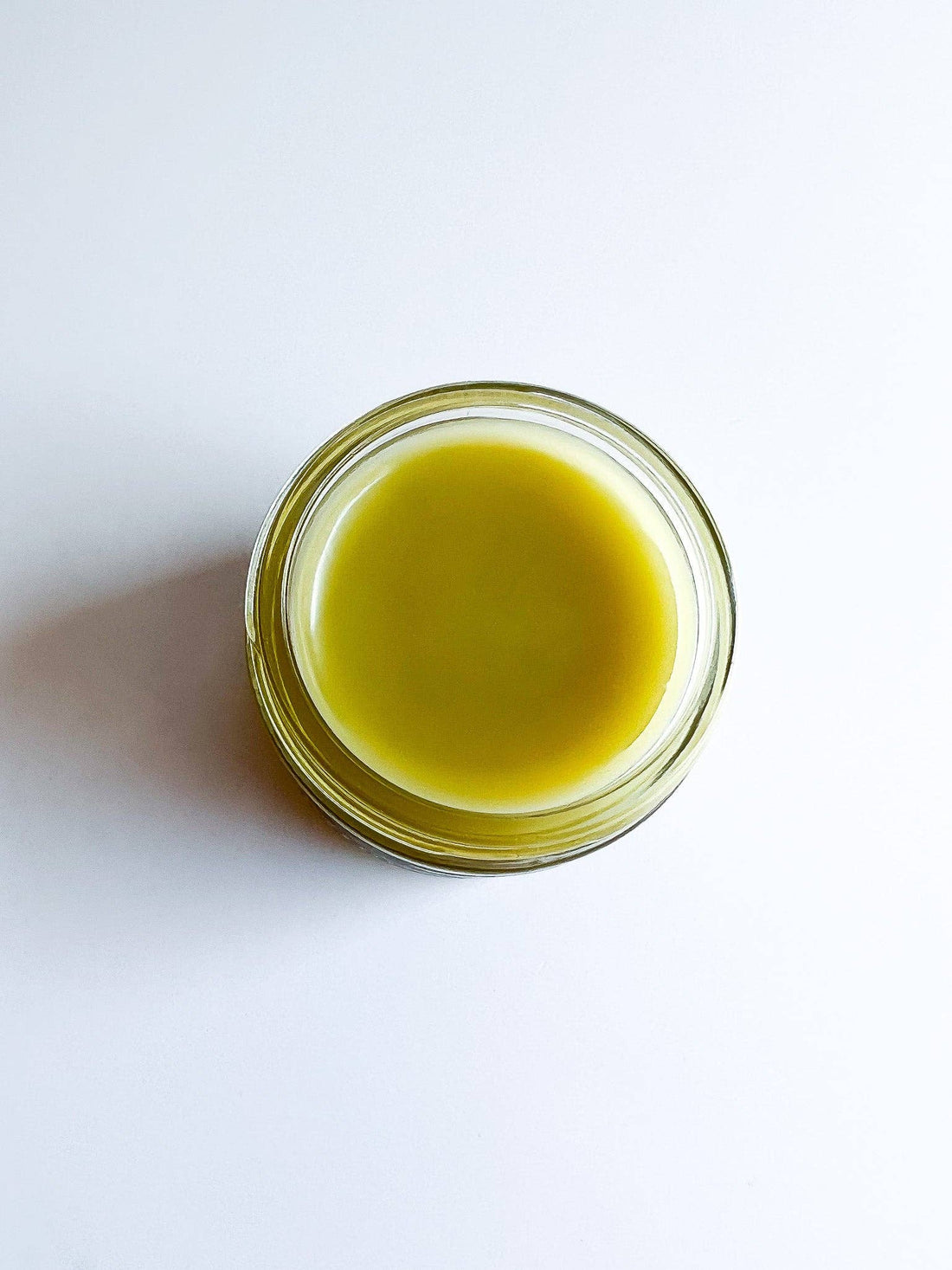 Glass jar with green liquid on a white background