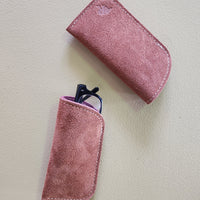 Rust suede eyeglass case with a smaller rust case containing glasses on a light gray background