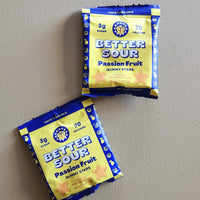 Two packs of Better Sour Passion Fruit Gummy Stars candy arranged on a neutral gray background.