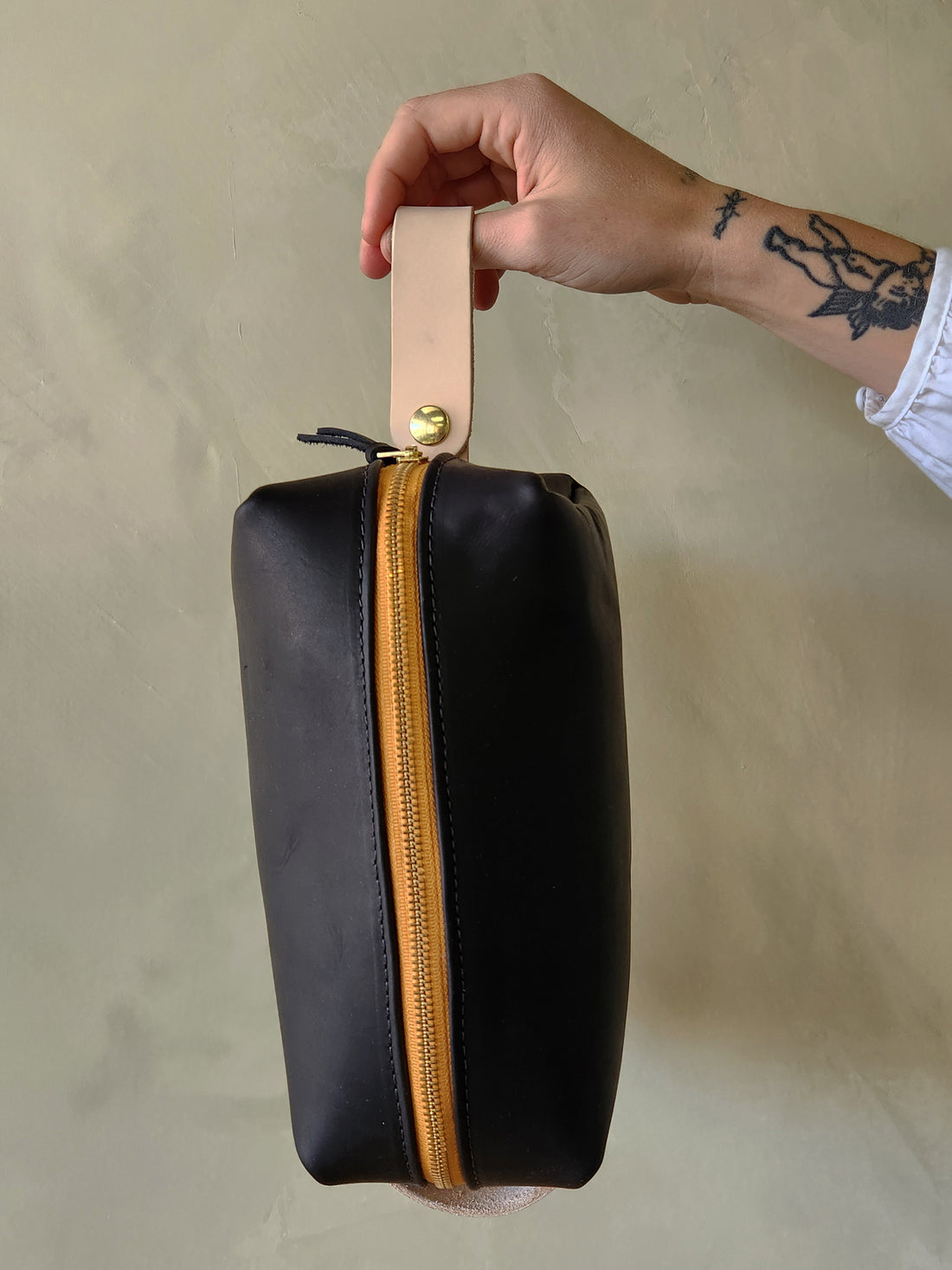 black leather dopp toiletry kit with yellow zipper. 