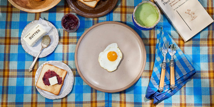 Breakfast setting with eggs, toast, and utensils on a plaid tablecloth