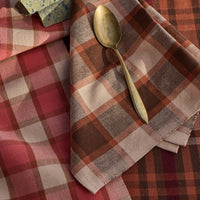 Gold spoon on a plaid fabric with a stone and folded fabric in the background