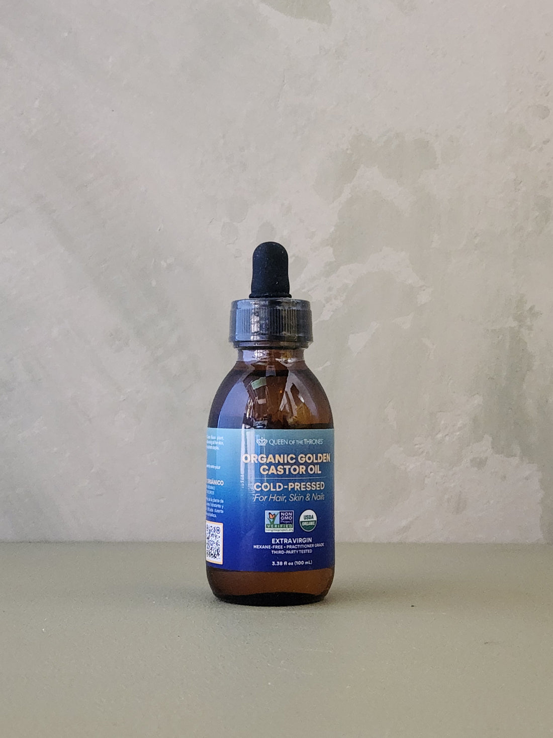 Bottle of organic golden castor oil on a neutral background