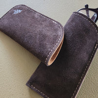 Brown suede glasses case on a light green surface