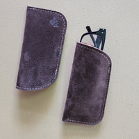 Two purple eyeglass cases on a light gray background