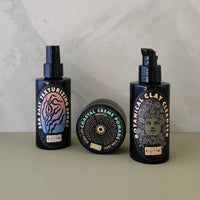 Three black haircare products from the brand Church: a texturizing spray, a clay cream, and a clay conditioner, arranged on a beige surface against a light gray marble-patterned background.