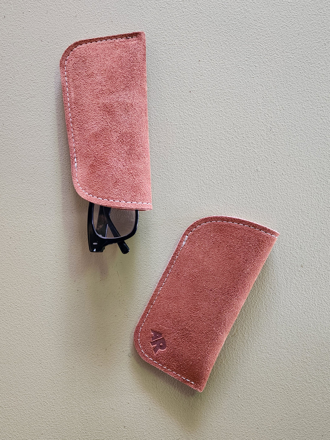 Two suede eyeglass cases on a light gray background