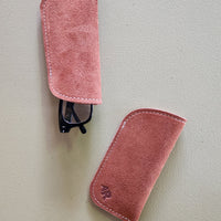 Two suede eyeglass cases on a light gray background