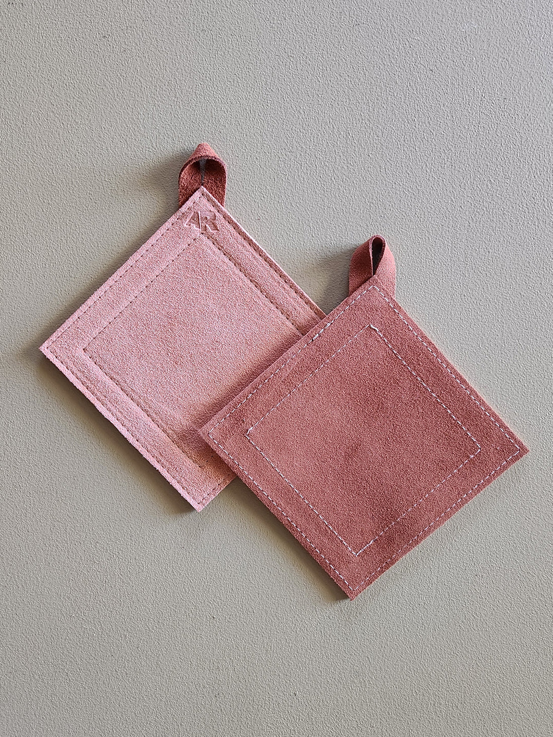 Two pink potholders on a light gray background