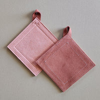 Two pink potholders on a light gray background
