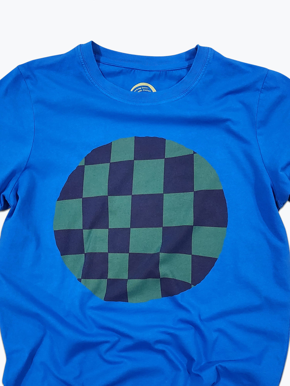 Blue t-shirt with a green and navy checkered circle design on a white background