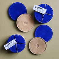 Set of 4 suede coasters, 1 side bright cobalt and the other side tan with AR brand. 