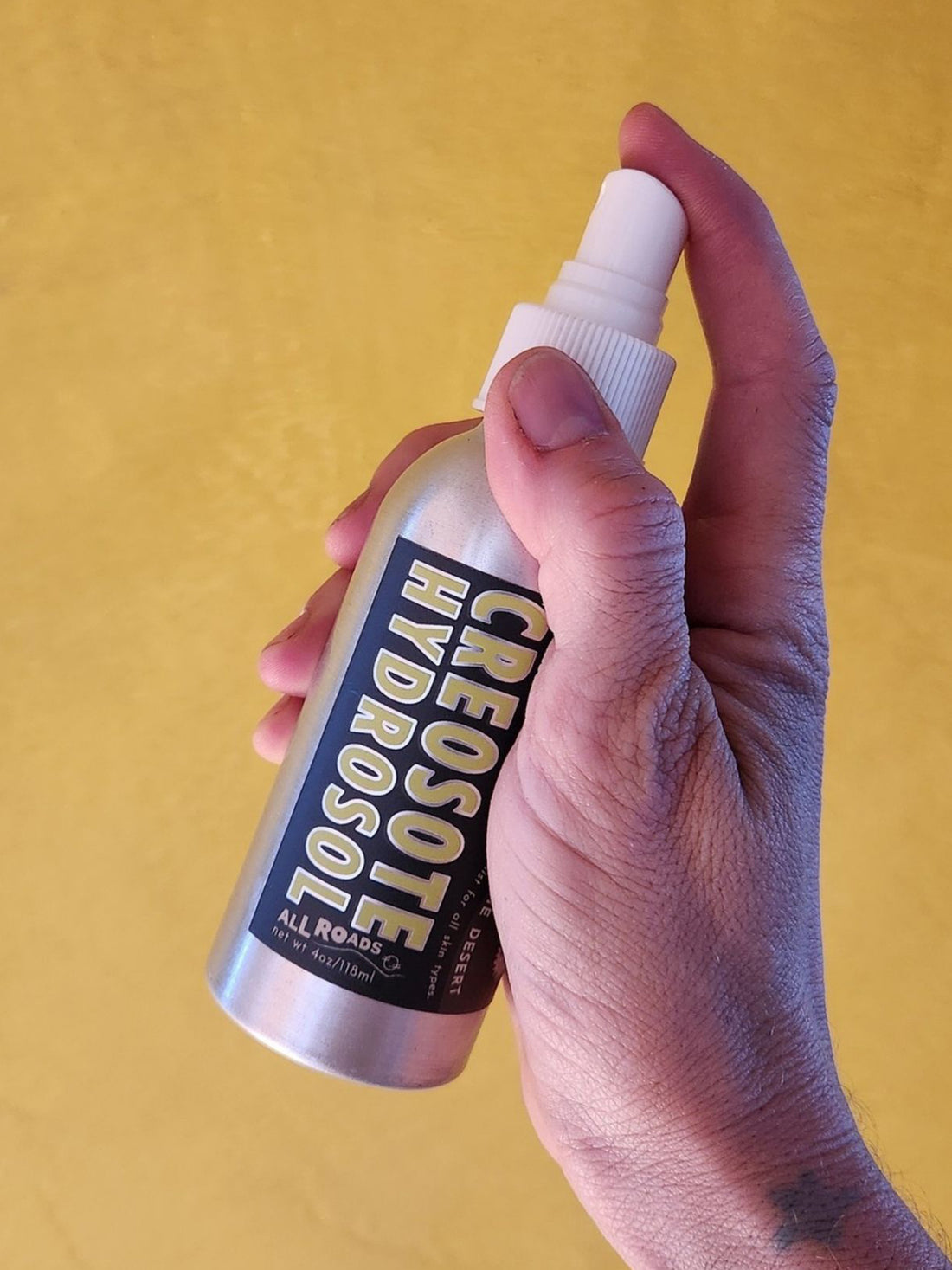 Hand holding a bottle labeled &