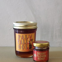 Two jars of honey with 'Palm Valley Gold' and 'Desert Flower Honey' labels on a neutral background.