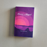 Purple book titled 'Desert Magick' on a light gray background
