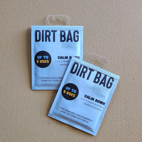 Two packages of 'Dirt Bag' on a beige background