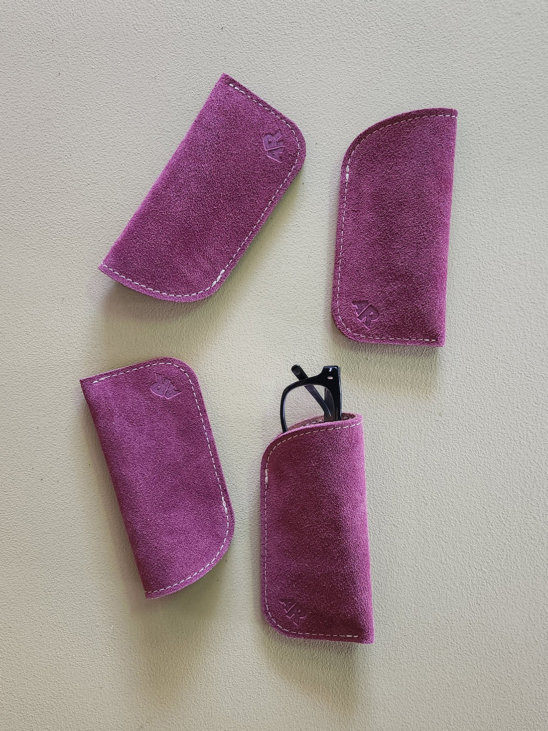 Four purple eyeglass cases on a light gray background