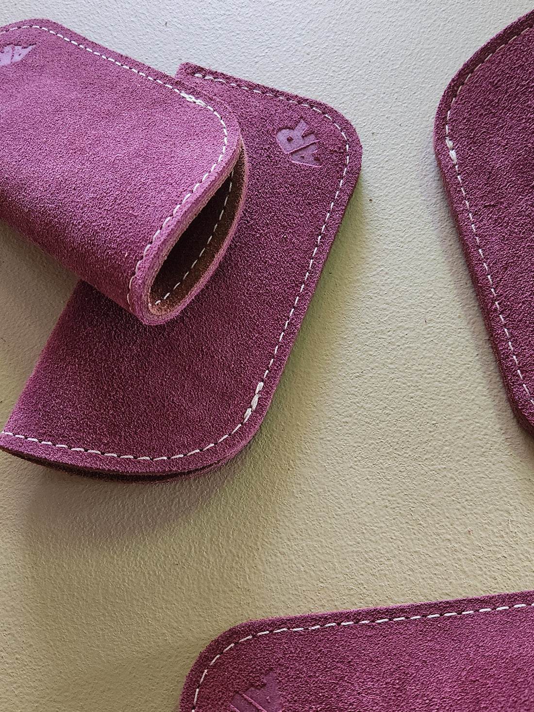 Close-up of purple suede eyeglass cases on a beige surface