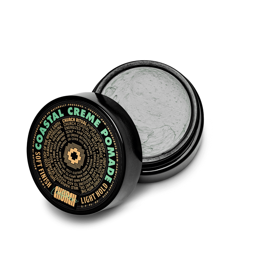 An open black jar of Church Coastal Creme Pomade with the lid leaning against it, showing a light gray pomade inside. The lid features a black label with green and gold text.