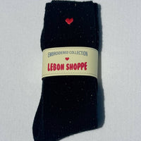 Black sock with a red heart and 'Lebon Shoppe' label on a light gray background