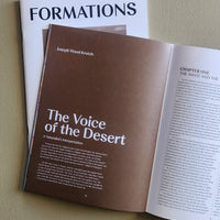 Open book titled 'The Voice of the Desert' by Joseph Wood Krutch on a beige surface with 'FORMATIONS' magazine.