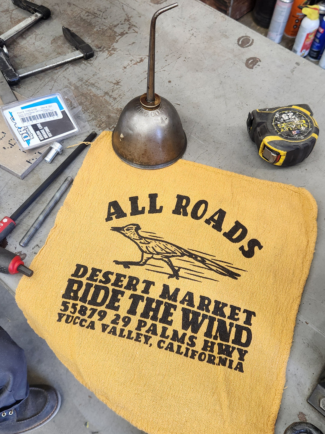 Yellow towel with text and logo on a workshop surface with tools.