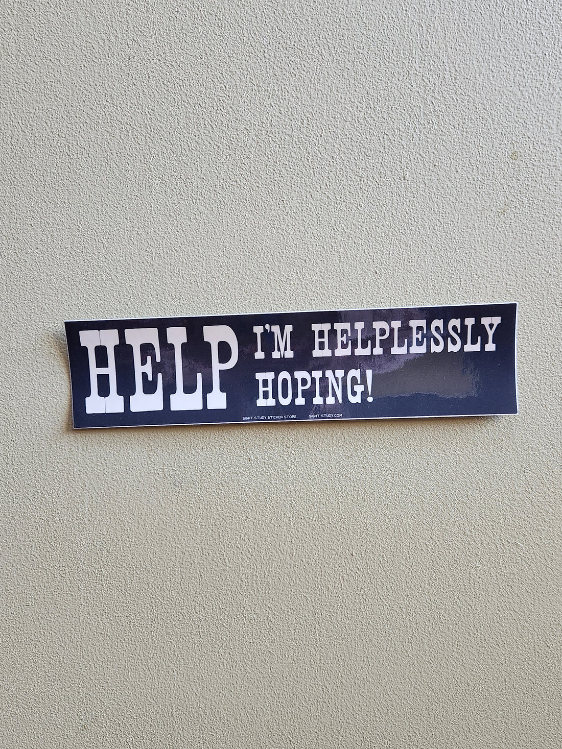 A dark blue bumper sticker with white text that reads &