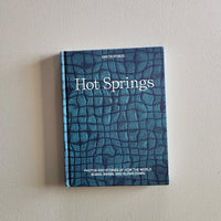 Book titled 'Hot Springs' with a textured blue cover on a light gray background