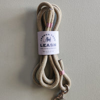 Beige dog leash with pink accents and a label on a gray background
