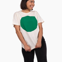Person wearing a white t-shirt with a large green circle on a white background