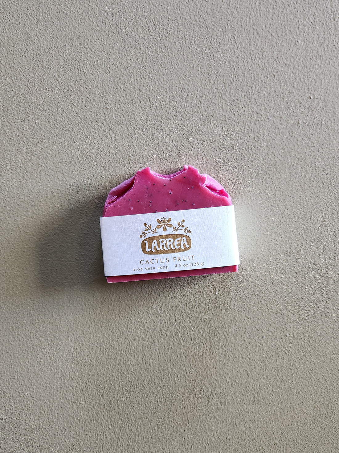 Pink soap bar with a Larrea label on a gray background
