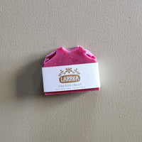 Pink soap bar with a Larrea label on a gray background