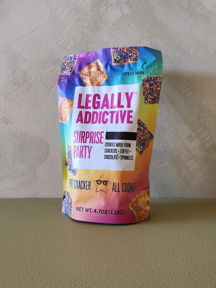 Colorful bag of 'Legally Addictive Surprise Party' cookies on a neutral background