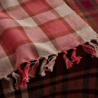 Plaid tablelinen with tassels on a plaid surface