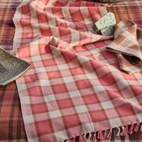 Plaid tablecloth with fringe on a table setting with strawberries and cheese.