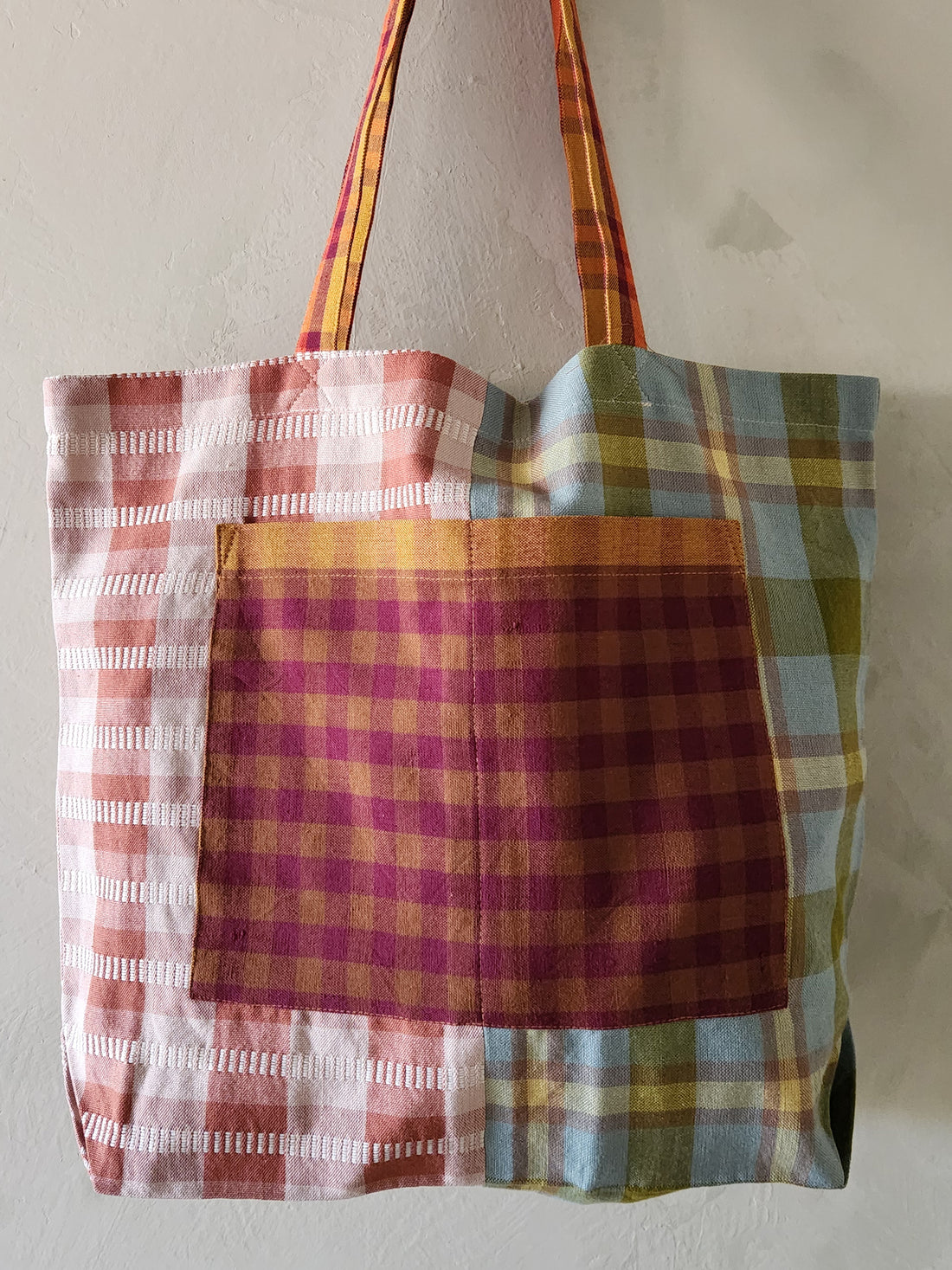 Plaid tote bag with colorful pattern on a plain background