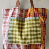 Multicolored plaid tote bag with a green checkered pocket on a light background