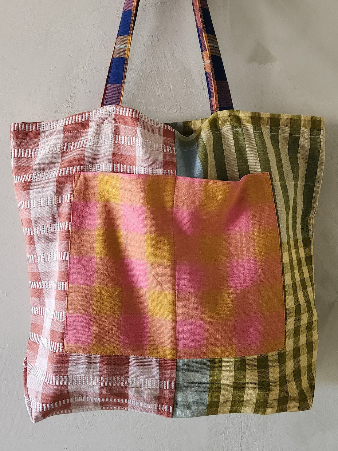 Colorful patchwork tote bag with plaid patterns on a plain background