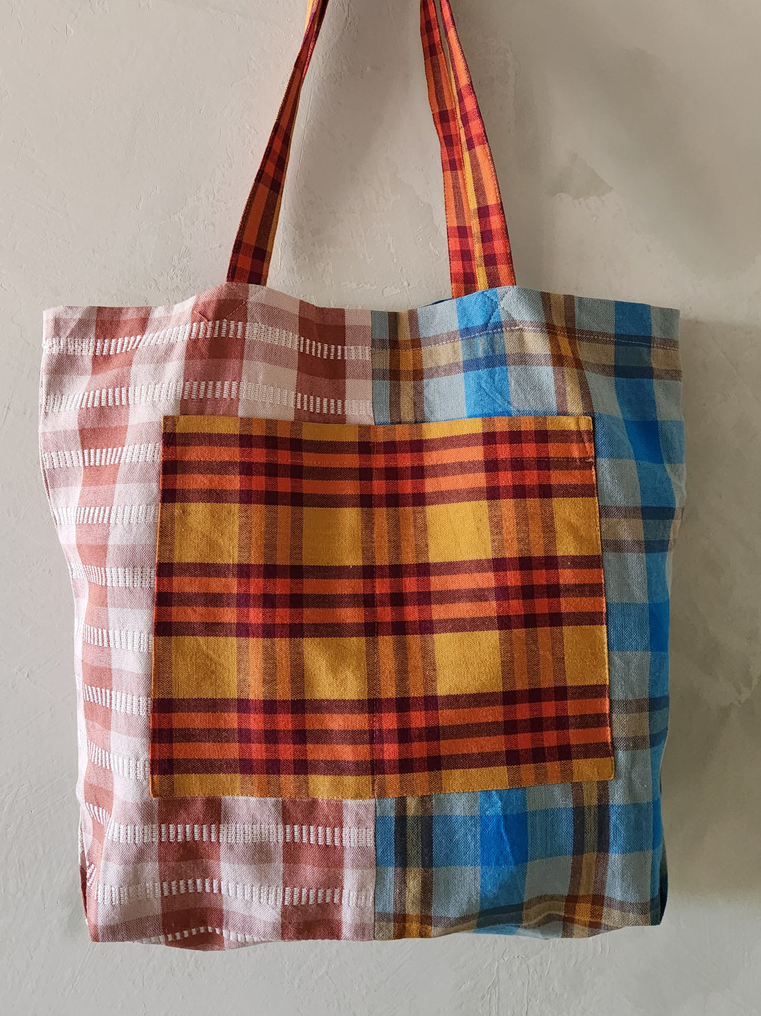 Plaid tote bag with red, blue, and yellow pattern on a plain background