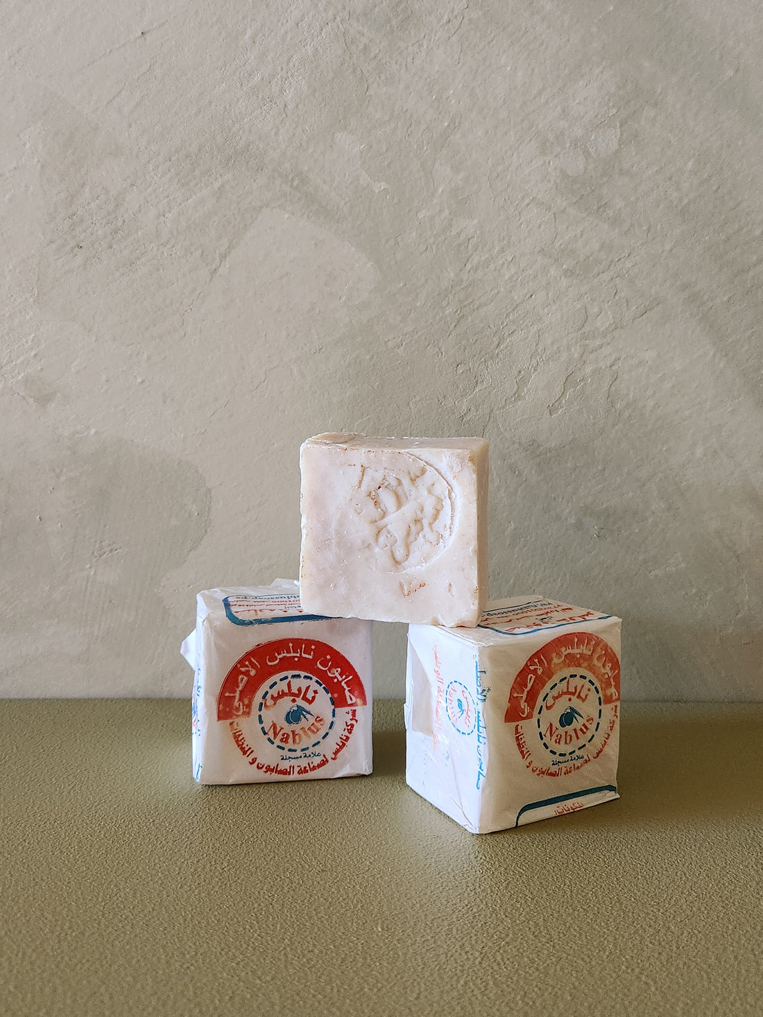 Three stacked soap bars with visible branding on a neutral background