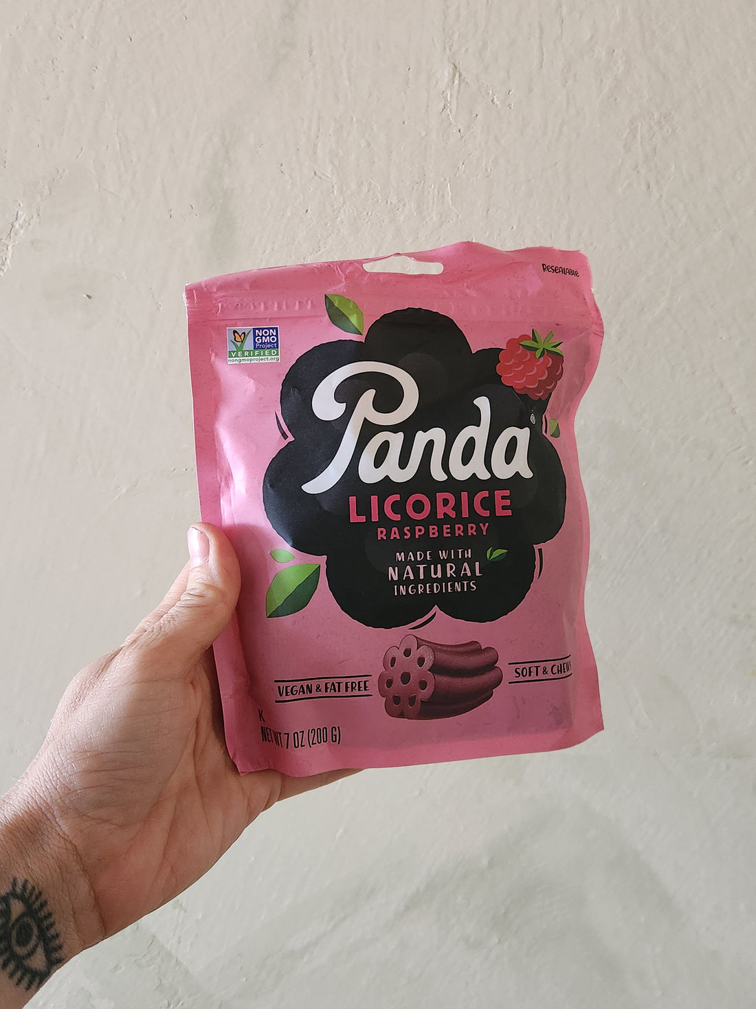A hand holding a pouch of Raspberry Licorice